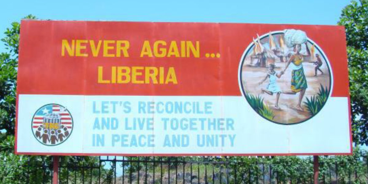 Roadside billboard in Liberia reading 'Never Again... Liberia. Let's reconcile and live together in peace and unity.'